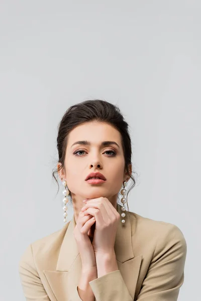 pretty young woman in pearl earrings looking at camera isolated on grey