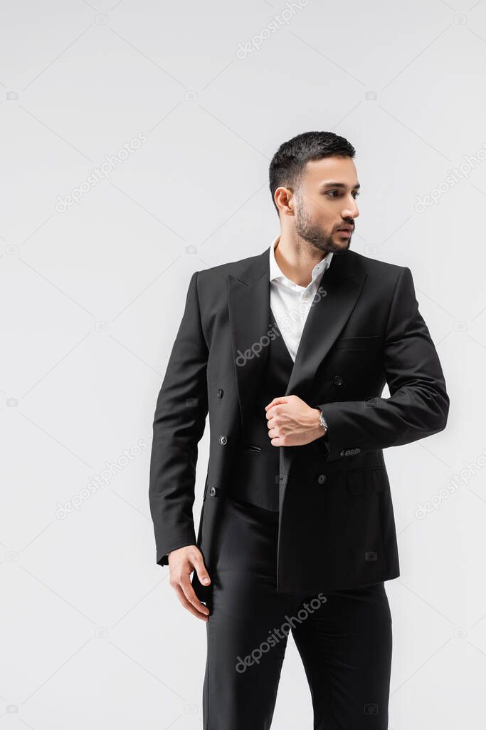 fashionable muslim man looking away while walking isolated on grey