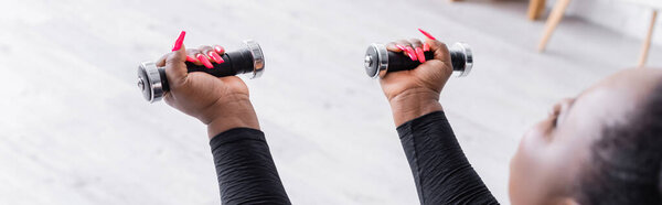 размытый африканский американец плюс размер женщины в спортивной форме упражнения с гантелями в гостиной, баннер