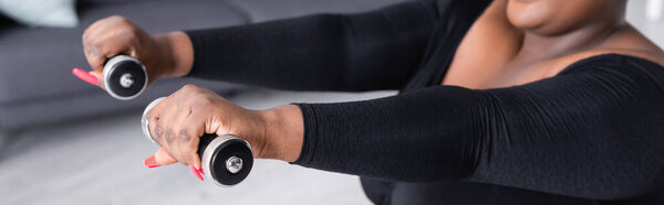 частичный взгляд на африканский американец плюс размер женщины в спортивной форме упражнения с гантелями, баннер