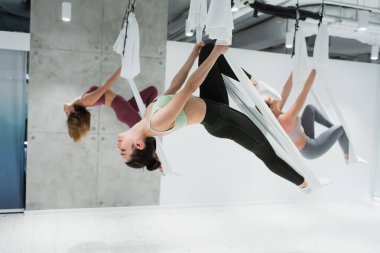 Spor merkezinde hava yogası yapan genç spor kadınları, bulanık arkaplan