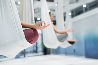 sportswomen meditating in lotus pose while practicing fly yoga, blurred background clipart