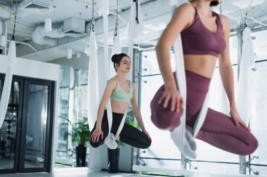 Nilüfer çiçeğinde meditasyon yapan spor kadınları hamaklarda sinek yogası yaparken, ön planda bulanıklık...
