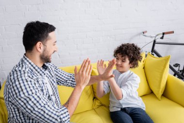 Neşeli Arap baba ve oğlu kanepede otururken pasta oyunu oynuyorlar.