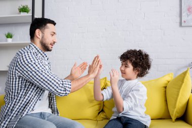 Müslüman çocuk ve babası kanepede oturup pasta oyunu oynuyorlar.
