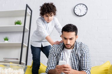 Arap çocuk evde akıllı telefondan ciddi baba mesajlarına bakıyor.