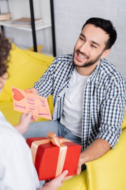Memnun Arap adam hediyesini alıyor ve seni seviyorum baba kartı oğlundan bulanık ön plan.