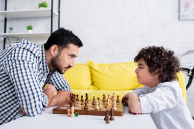 Müslüman baba ve oğulun yan bakışı. Satrancın yanında birbirlerine bakıyorlar. 