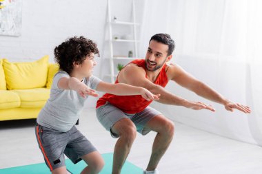 Neşeli Arap baba ve oğlu evde egzersiz yapıyor. 