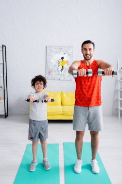 Halterli Arap adam antrenmanı, oğlunun yanında spor minderinde. 