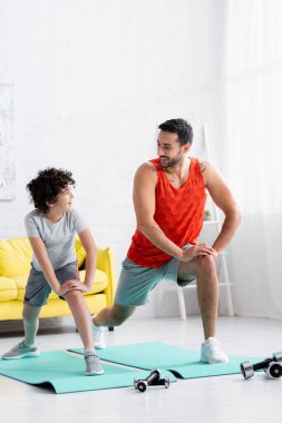 Müslüman baba oğluna gülümsüyor oturma odasında hamle yapıyor. 