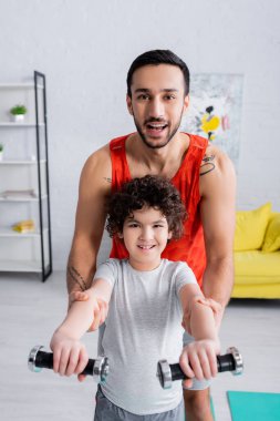 Mutlu Müslüman baba, evdeki dambıllara yardım ediyor. 