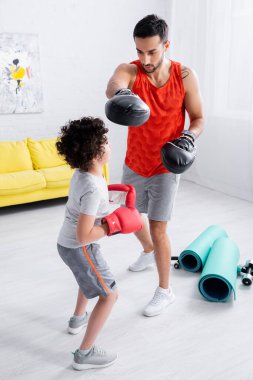 Müslüman baba ve oğul evde spor malzemelerinin yanında boks yapıyor. 