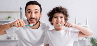 Gülümseyen Arap adam ve oğlu diş fırçalıyorlar, afiş 