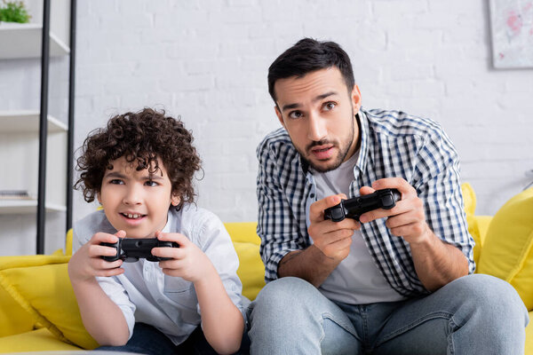 КИЕВ, УКРАИНА - 15 ЯНВАРЯ 2021 года: сосредоточенные мусульманские отец и сын играют вместе дома