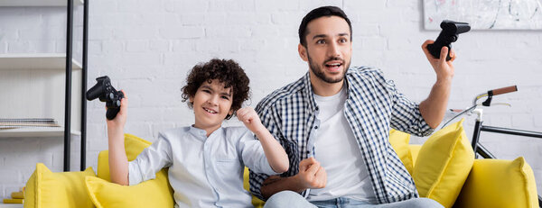 КИЕВ, УКРАИНА - 15 ЯНВАРЯ 2021: взволнованные арабский папа и сын показывая жест победы во время проведения джойстиков, баннер