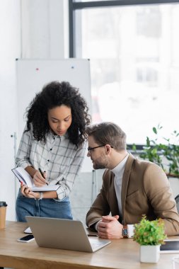Aygıtların yanında defterle çalışan ırklar arası iş adamları ve içecek servisi. 
