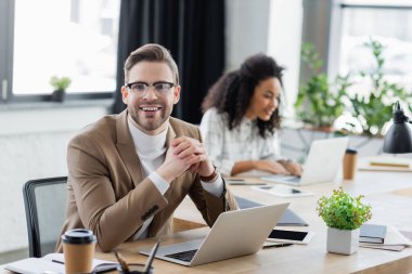 Cihazların yanındaki kameraya bakan neşeli iş adamı ve ofise gitmek için kahve. 