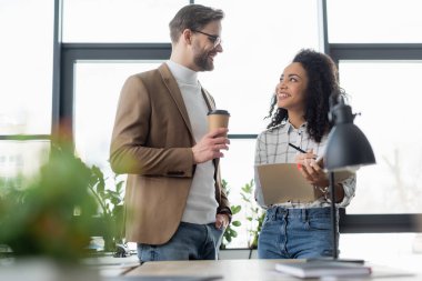 Kahveli ve gazeteli çok ırklı iş adamları güler. 