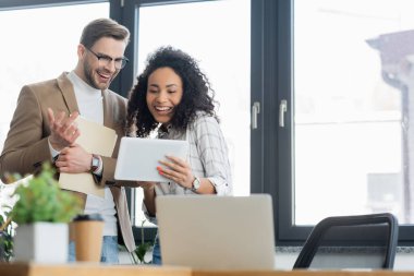 Ofiste dijital tablet kullanan neşeli ırklar arası iş adamları 