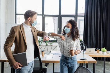 Ofiste dirsek teması sırasında birbirine bakan ırklar arası iş arkadaşları.