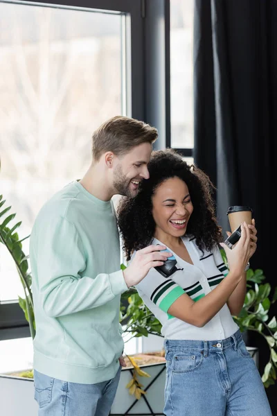 laughing african american manager showing automatic stamp to smiling colleague