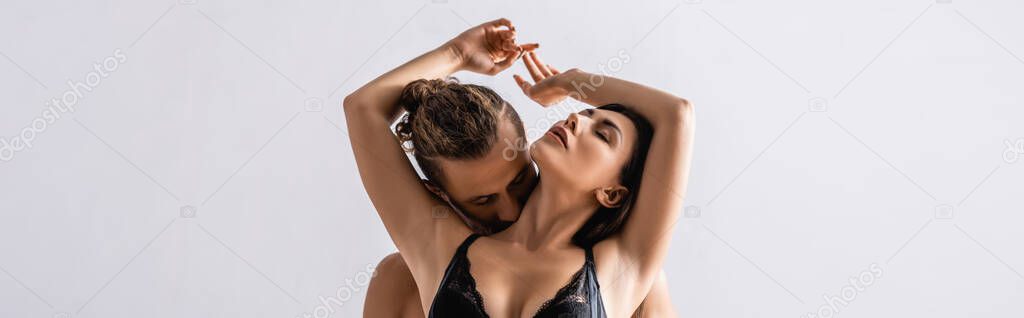 Sexy man kissing neck of passionate woman isolated on grey, banner 