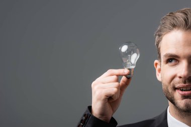 cropped view of positive businessman holding light bulb isolated on grey clipart