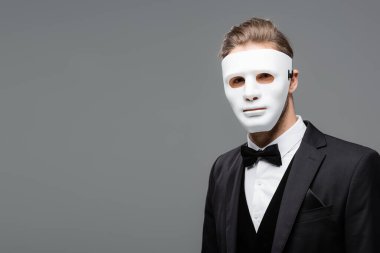 young businessman in face mask looking at camera isolated on grey clipart