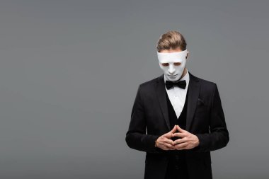 businessman in face mask standing with joined fingers isolated on grey clipart