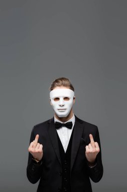 businessman in face mask showing middle fingers isolated on grey clipart