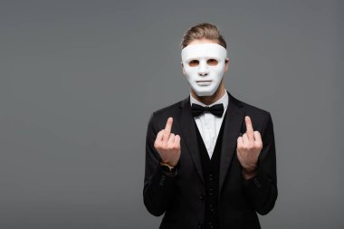 businessman showing middle fingers while wearing face mask isolated on grey clipart