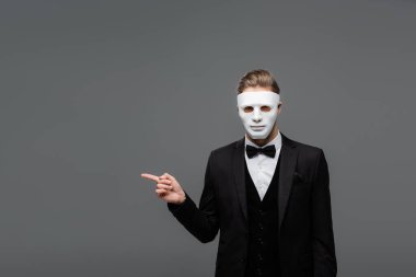 elegant businessman in face mask pointing with finger isolated on grey clipart