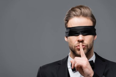 Gözü bağlı işadamı Gri üzerine izole edilmiş sessizlik işareti gösteriyor