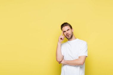 Düşünceli adam başını çeviriyor ve sarıda dikilirken başına dokunuyor