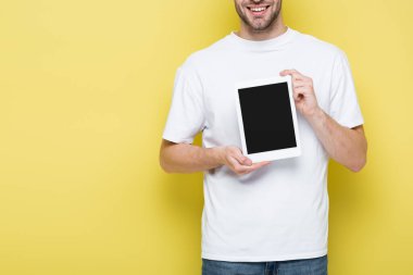 Sarı ekranda boş ekranlı dijital tablet gösteren neşeli adamın kısmi görüntüsü