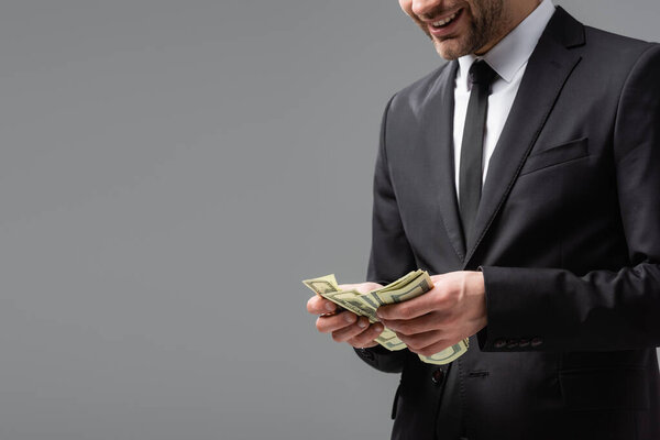 частичный взгляд бизнесмена в черном костюме, считая доллары, изолированные на сером