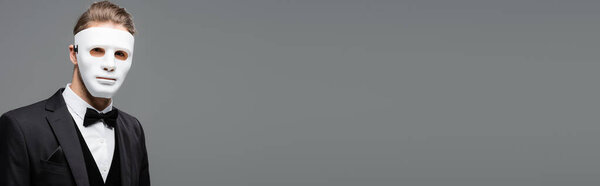 businessman in face mask looking at camera isolated on grey, banner