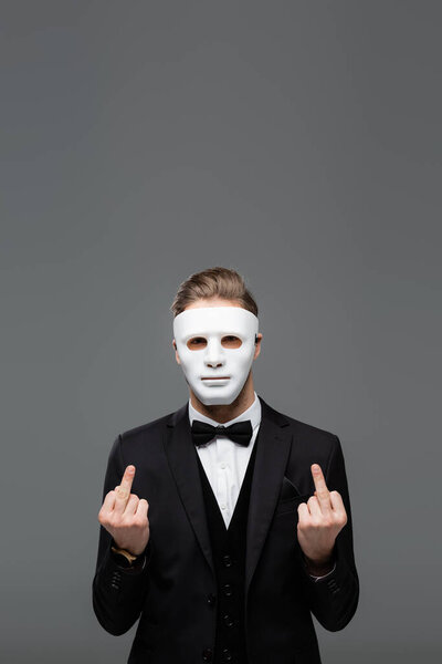 businessman in face mask showing middle fingers isolated on grey