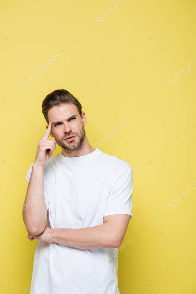 thoughtful man looking away and touching head on yellow