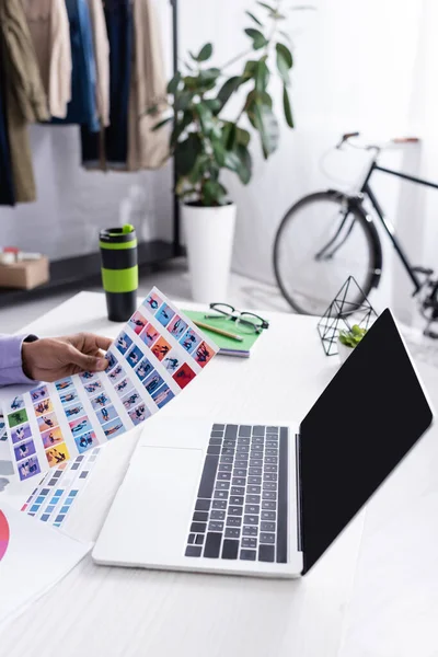 Afro-Amerikan galeri sahibinin dizüstü bilgisayarın yanında boş ekranlı bir kitap tutuşu. 