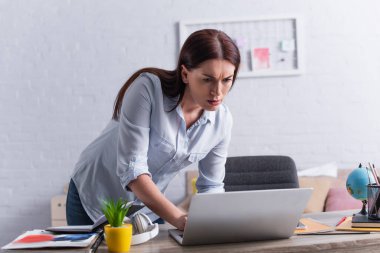 woman looking at laptop while sneaking around at home clipart