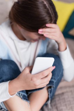 Bulanık ve üzgün genç kızın elinde akıllı telefon. 