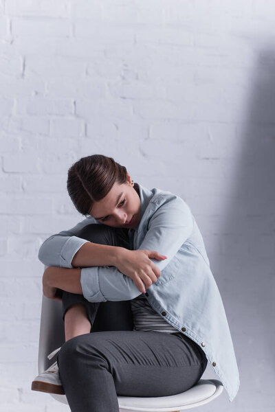 upset teenage girl sitting on chair and looking away