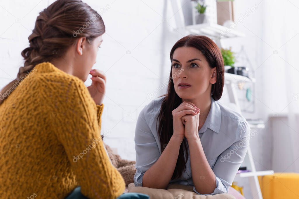 worried mother looking at teenage daughter on blurred foreground