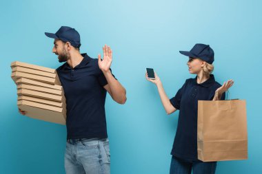 Arap kurye atık jesti gösteriyor. Kuryenin yanında. Akıllı telefonu mavi üzerine tutuyor.