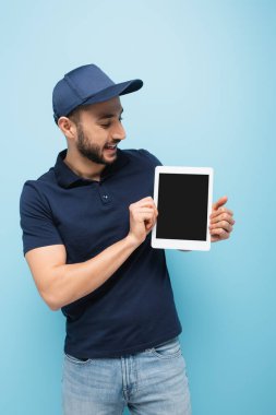 Neşeli Müslüman teslimatçı elinde mavi ekranlı dijital tablet tutuyor.