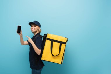 Termo sırt çantalı güzel kurye mavi ekranlı akıllı telefonu gösteriyor.