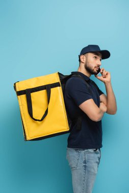 Termal çantalı Müslüman kurye cep telefonuyla mavi hattan konuşuyor.