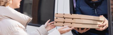 Arabadaki teslimatçıdan pizza kutularını alan kadın manzarası.